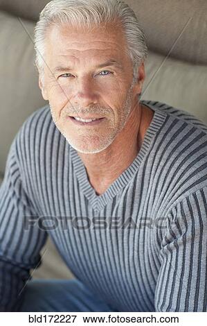 Stock Photo - Caucasian man sitting on sofa. Fotosearch