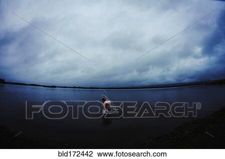Stock Image - Caucasian man splashing in still remote lake. Fotosearch