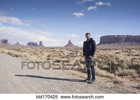 Stock Photography - Caucasian man standing on desert dirt road. Fotosearch