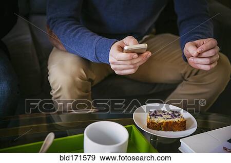 Stock Photo - Caucasian man using cell phone at breakfast. Fotosearch