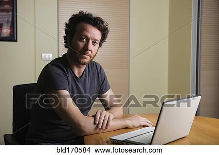 Picture - Caucasian man using laptop on desk. Fotosearch