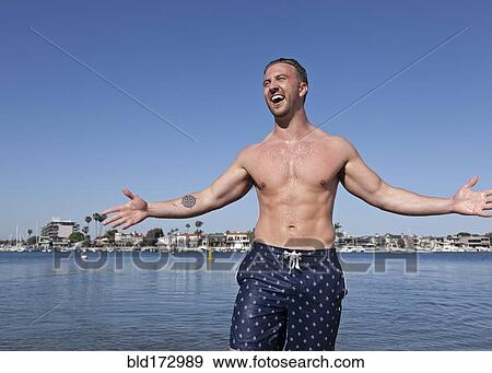 Stock Photo - Caucasian man wearing swimsuit on beach. Fotosearch