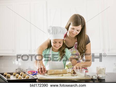 Stock Image - Caucasian mother and daughter baking in kitchen. Fotosearch