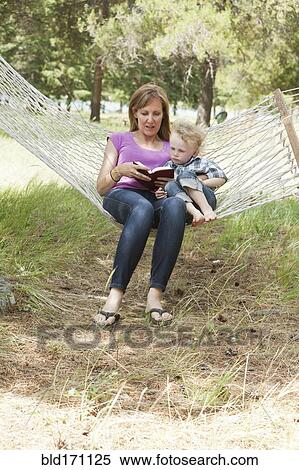 Stock Photography - Caucasian mother and son reading in hammock. Fotosearch
