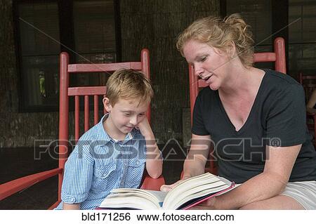 Stock Photograph - Caucasian mother and son reading on patio. Fotosearch
