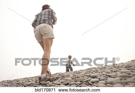 Stock Image - Caucasian mother and son walking on rocky hillside. Fotosearch