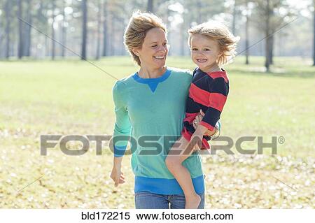 Stock Photography - Caucasian mother carrying daughter in park. Fotosearch