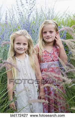 Stock Photo - Caucasian sisters standing in tall grass. Fotosearch