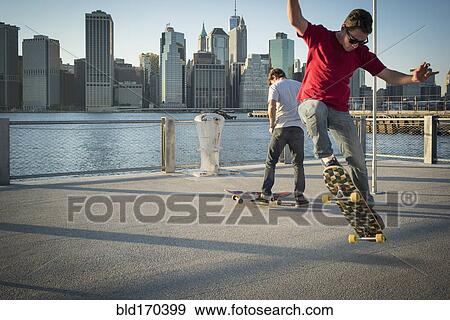 Caucasian skateboarders doing tricks at waterfront, New York, United States View Large Photo Image Stock Photo - Caucasian skateboarders doing tricks at waterfront, New York, United States. Fotosearch