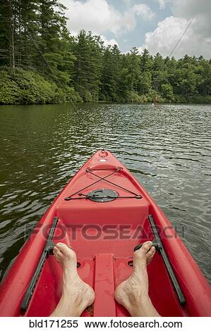 Stock Photography - Caucasian teenage boy sitting in canoe on lake. Fotosearch