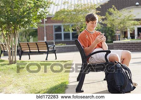 Caucasian teenage boy using cell phone on bench View Large Photo Image Stock Image - Caucasian teenage boy using cell phone on bench. Fotosearch