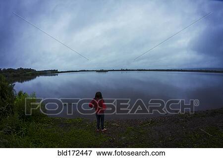 Stock Photo - Caucasian teenage girl standing by remote lake. Fotosearch