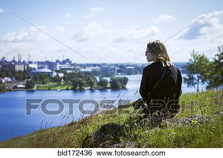 Stock Photograph - Caucasian woman admiring cityscape from rural hilltop. Fotosearch