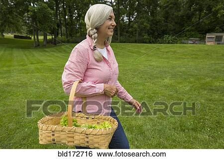 Caucasian woman carrying basket of vegetables in garden View Large Photo Image Stock Photograph - Caucasian woman carrying basket of vegetables in garden. Fotosearch