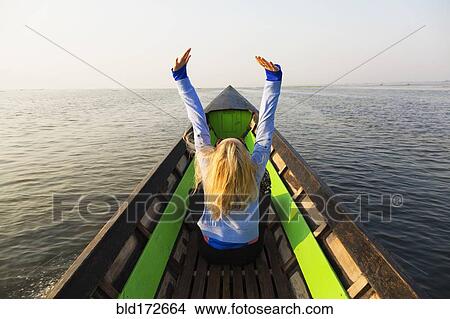 Picture - Caucasian woman cheering in canoe on lake. Fotosearch