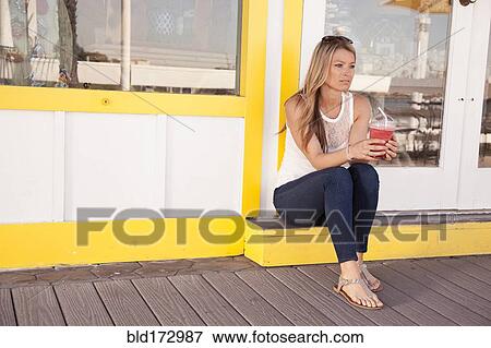 Caucasian woman drinking juice outside restaurant View Large Photo Image Stock Photo - Caucasian woman drinking juice outside restaurant. Fotosearch