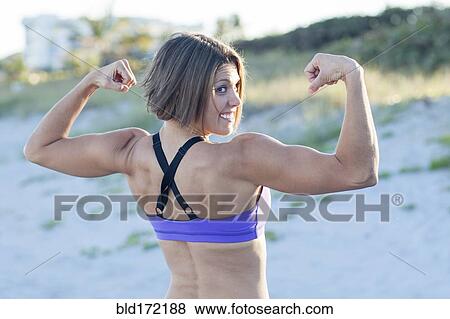 Caucasian woman flexing muscles on beach View Large Photo Image Stock Photo - Caucasian woman flexing muscles on beach. Fotosearch