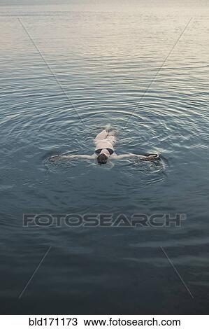 Caucasian woman floating in still lake View Large Photo Image Stock Image - Caucasian woman floating in still lake. Fotosearch
