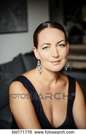 Stock Photograph - Caucasian woman in evening gown sitting on sofa. Fotosearch