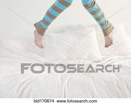 Picture - Caucasian woman jumping on bed. Fotosearch
