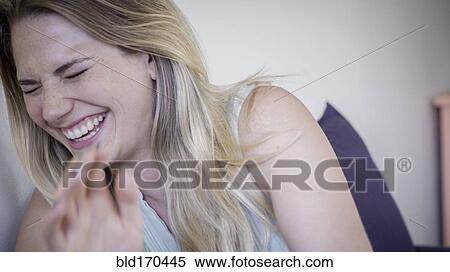 Stock Photography - Caucasian woman laughing in living room. Fotosearch