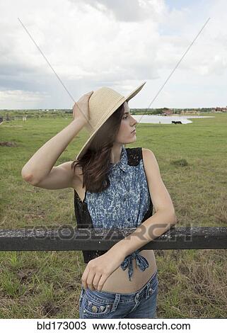 Stock Image - Caucasian woman leaning on fence in rural pasture. Fotosearch