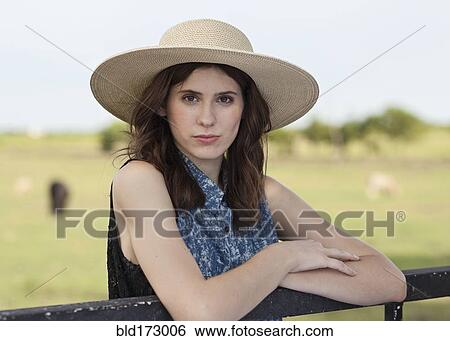Stock Photograph - Caucasian woman leaning on fence in rural pasture. Fotosearch