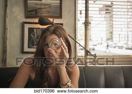 Stock Photograph - Caucasian woman looking through empty glass in cafe. Fotosearch