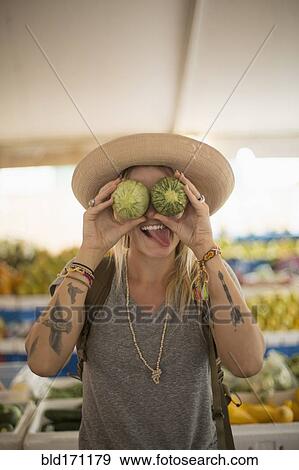 Caucasian woman making a face with fruit in farmers market View Large Photo Image Stock Photo - Caucasian woman making a face with fruit in farmers market. Fotosearch