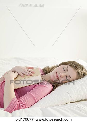 Caucasian woman napping with book on bed View Large Photo Image Stock Photo - Caucasian woman napping with book on bed. Fotosearch