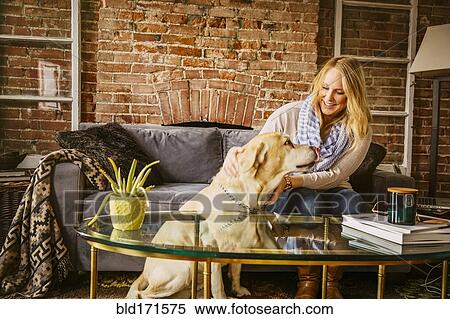 Stock Photography - Caucasian woman petting dog in living room. Fotosearch