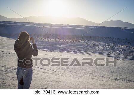 Stock Image - Caucasian woman photographing White Sands National Park, New Mexico, United States. Fotosearch