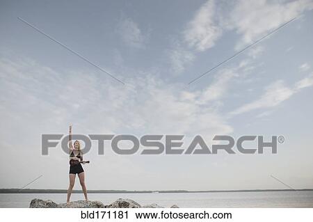 Stock Image - Caucasian woman playing ukulele by remote lake. Fotosearch
