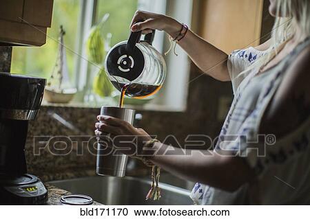 Stock Image - Caucasian woman pouring cup of coffee in kitchen. Fotosearch