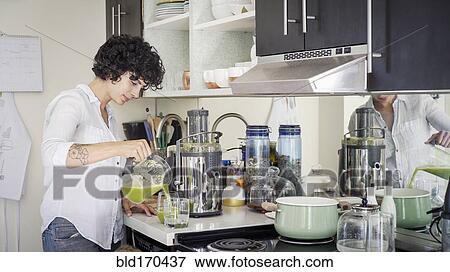 Stock Photo - Caucasian woman pouring juice in kitchen. Fotosearch