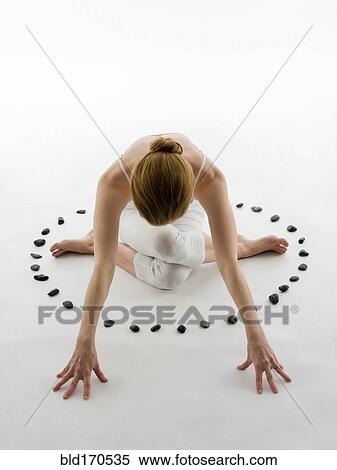 Stock Photography - Caucasian woman practicing yoga in ring of stones. Fotosearch