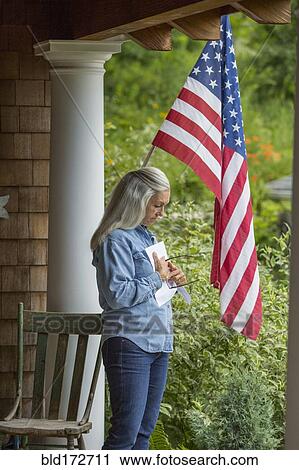 Stock Image - Caucasian woman reading letter on porch. Fotosearch