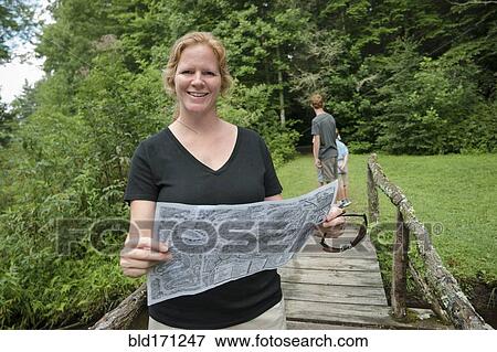 Caucasian woman reading map on footbridge in forest View Large Photo Image Stock Photo - Caucasian woman reading map on footbridge in forest. Fotosearch