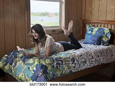 Caucasian woman reading on bed in dorm room View Large Photo Image Stock Image - Caucasian woman reading on bed in dorm room. Fotosearch