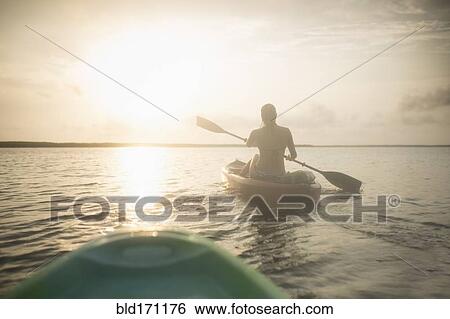 Caucasian woman rowing canoe on still lake View Large Photo Image Stock Photograph - Caucasian woman rowing canoe on still lake. Fotosearch