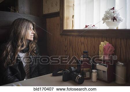 Stock Photo - Caucasian woman sitting in diner booth near window. Fotosearch