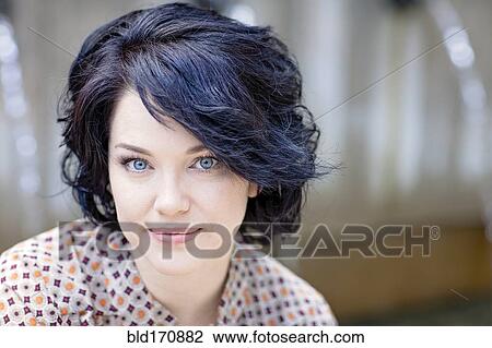 Stock Image - Caucasian woman sitting outdoors. Fotosearch