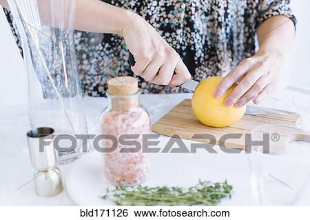 Stock Photograph - Caucasian woman slicing fruit on counter. Fotosearch