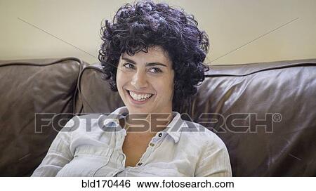 Stock Photograph - Caucasian woman smiling on sofa. Fotosearch