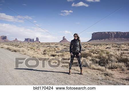 Picture - Caucasian woman standing on desert dirt road. Fotosearch