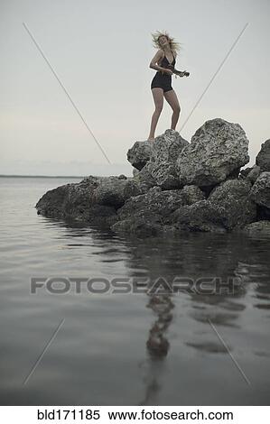 Stock Photography - Caucasian woman standing on rocks by remote lake. Fotosearch