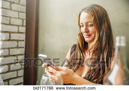 Stock Photo - Caucasian woman using cell phone in restaurant. Fotosearch