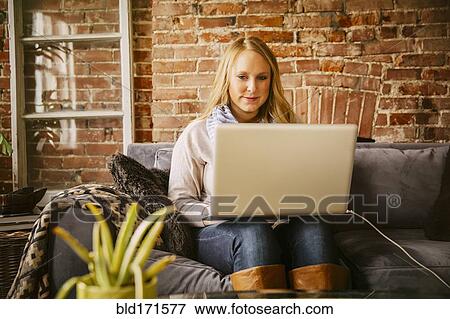 Stock Photo - Caucasian woman using laptop on sofa. Fotosearch