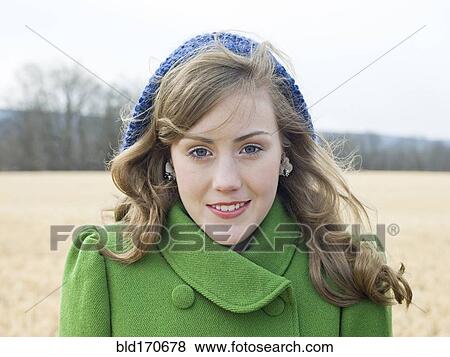 Stock Photo - Caucasian woman wearing coat and hat in field. Fotosearch