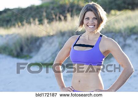 Stock Photo - Caucasian woman wearing sports bra on beach. Fotosearch